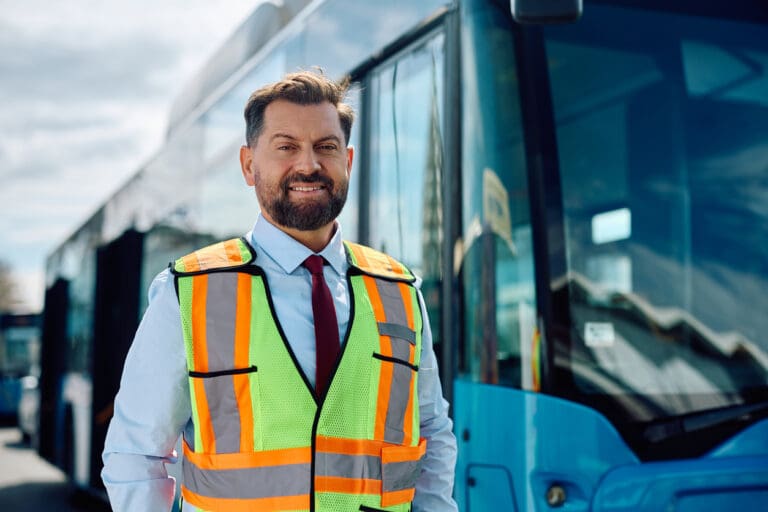 Smiling bus driver in front of bus